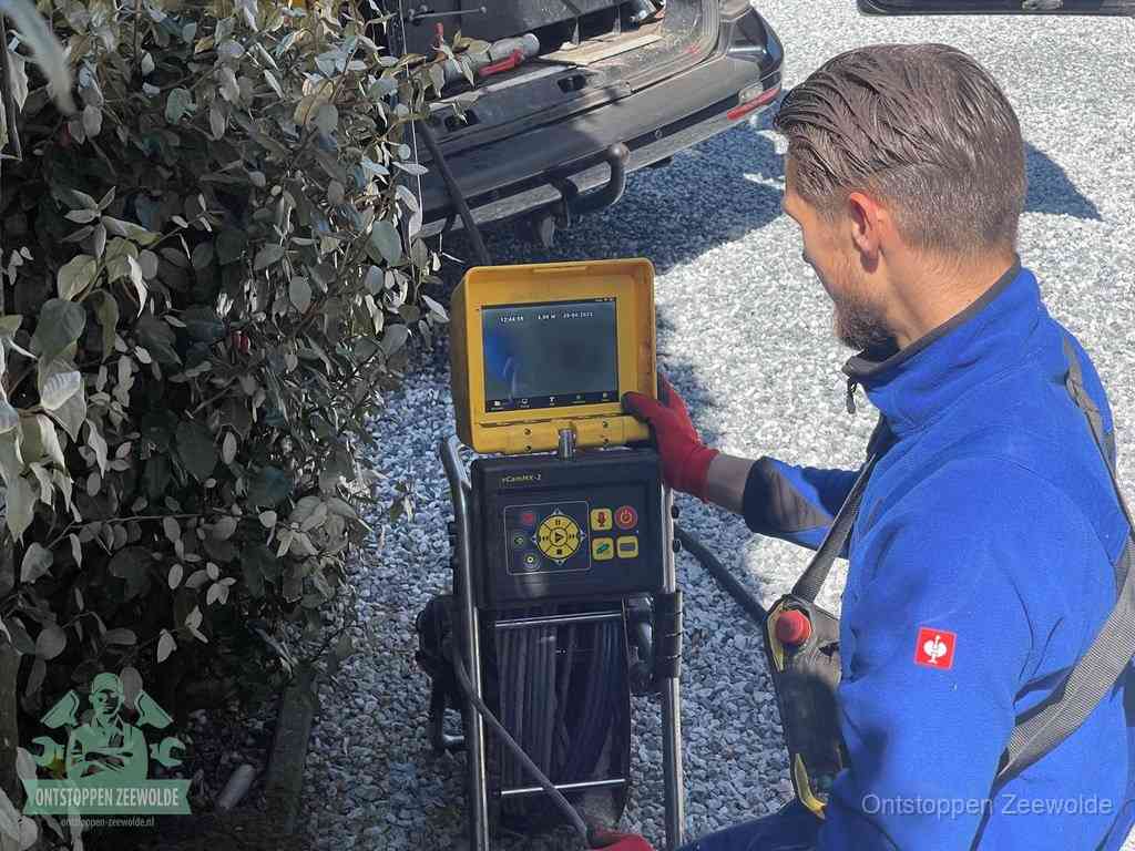 Een monteur bedient een rioolinspectiecamera met monitor en haspel om de verstopping in beeld te brengen in Zeewolde