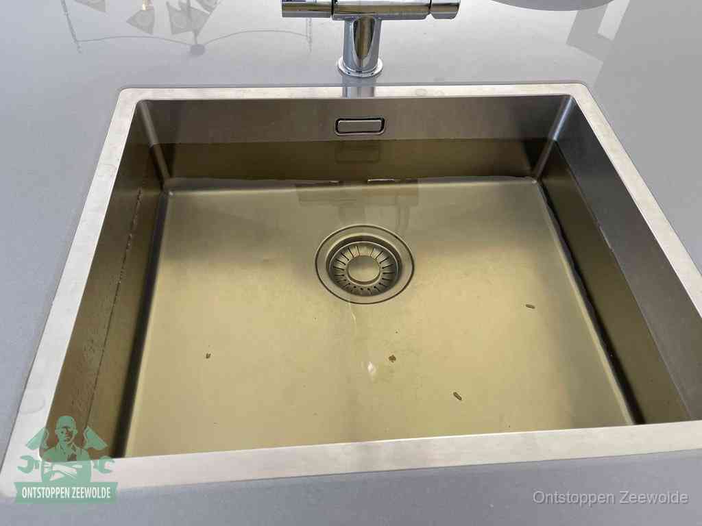 Een RVS spoelbak met stilstaand water dat niet wegloopt, een van de eerste signalen van een beginnende verstopping in Zeewolde