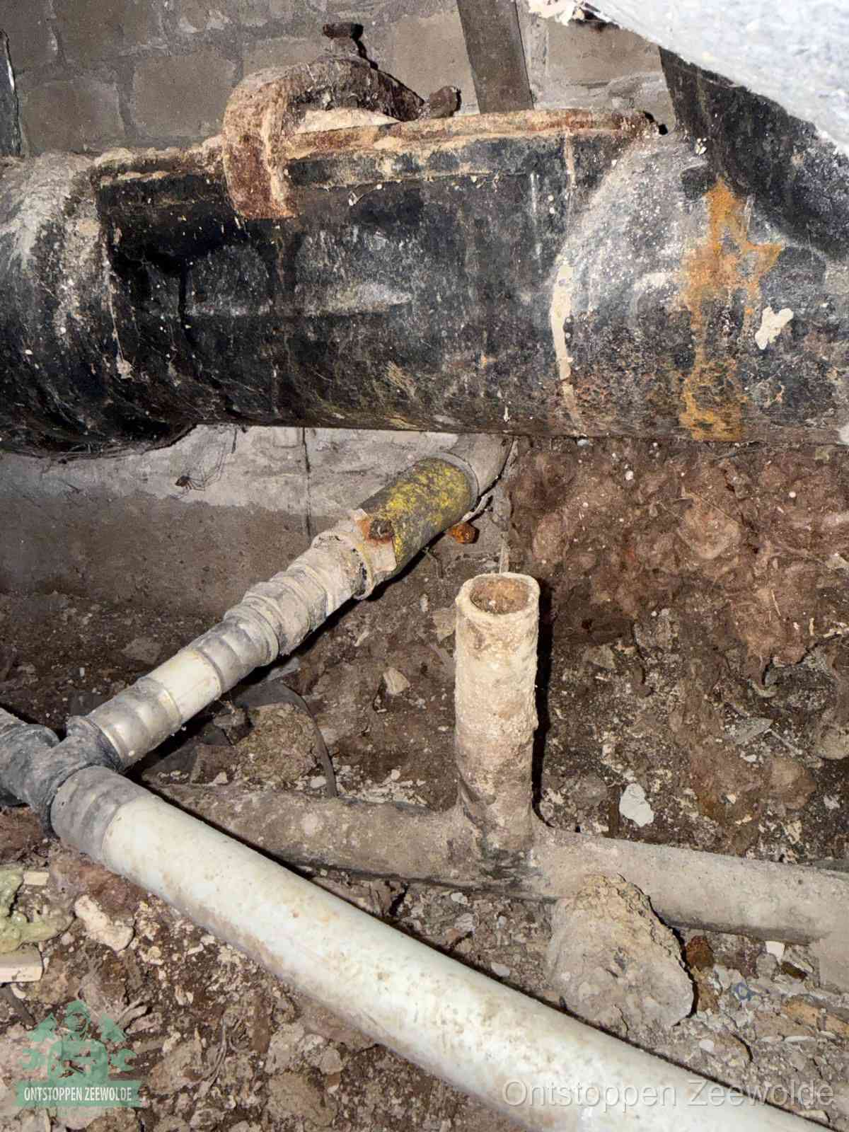 Een oude hoofdrioolbuis met roest- en kalkaanslag in een kruipruimte, oorzaak van terugkerende structurele rioolproblemen in Zeewolde