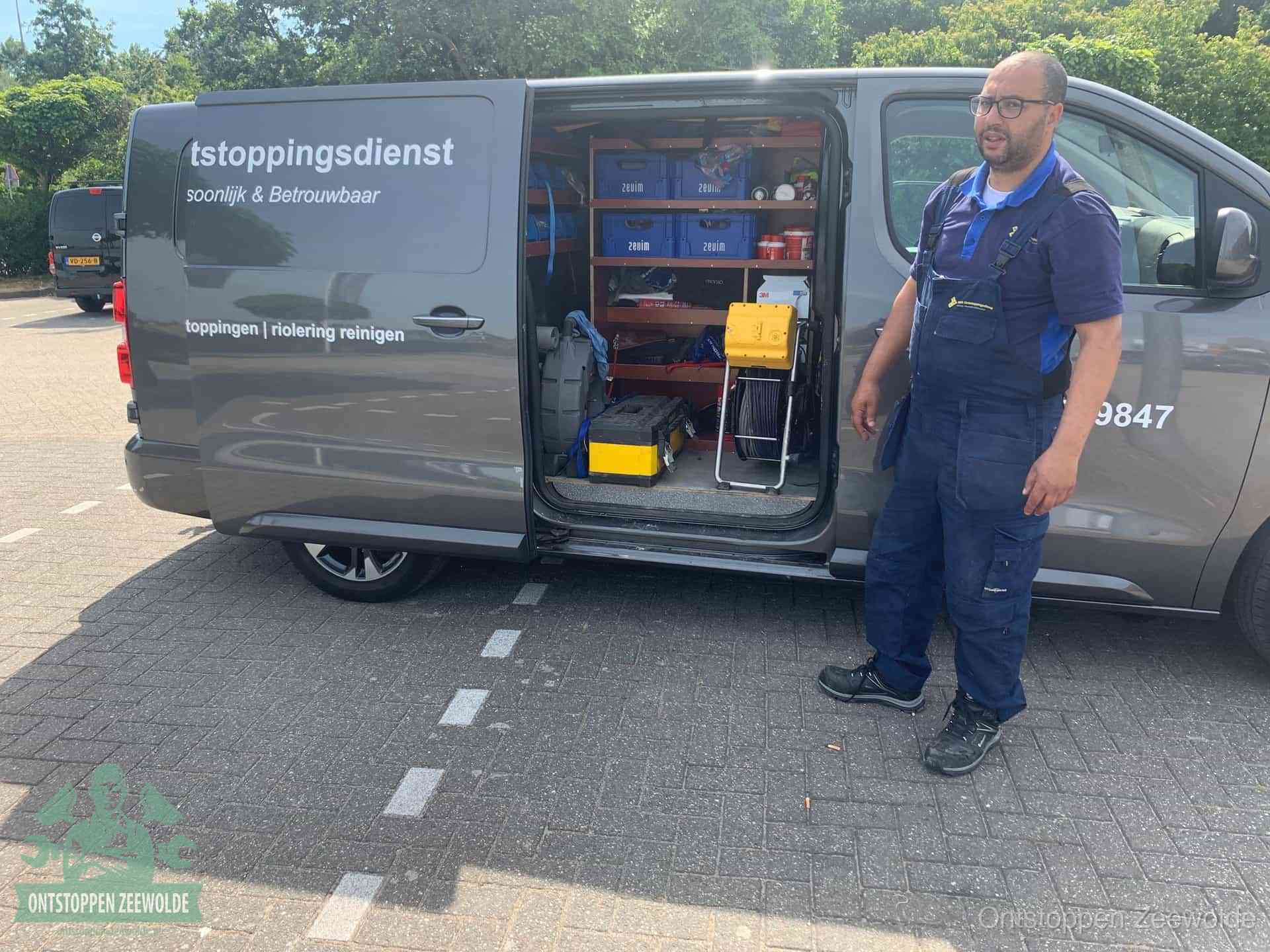 Een monteur staat klaar bij zijn bedrijfsbus met gereedschap, de vaste werkwijze van de ontstoppingsdienst in Zeewolde